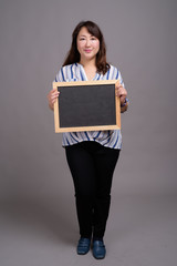 Japanese businesswoman holding empty blackboard with copyspace