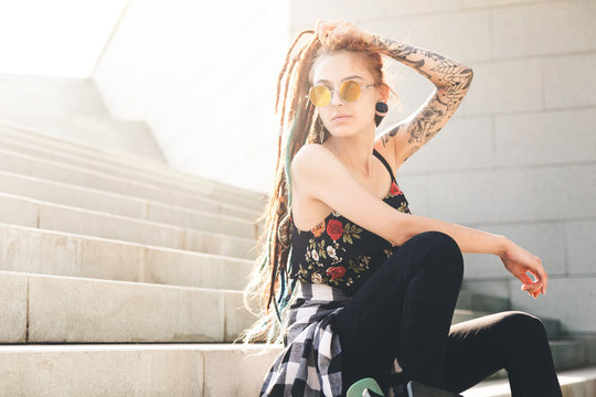 young girl with tattoo and dreadlocks sitting on the steps