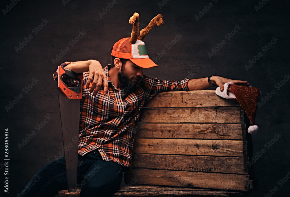 Wall mural Carpenter wearing decorated christmas cap sitting on a wooden palette.