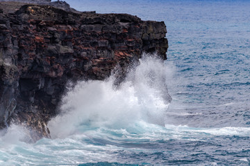 Large waves crashing against tall volcanic cliffs on Hawaii's Big Island, Below Chain of Craters road in Volcano National Park. Pacific ocean in the background.