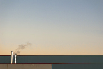 Naklejka na ściany i meble Chimneys or smokestack of an industrial factory emitting gases and smoke to the environment at sunset. Concept of air pollution with copy space.