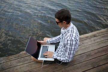 Photo of man with laptop on river bank