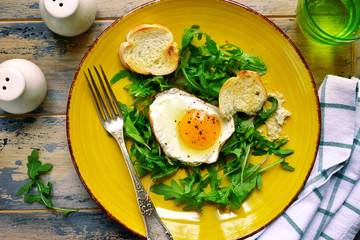 Bright healthy breakfast - mix of salad leaves, fried egg and baguette.Top view with copy space.