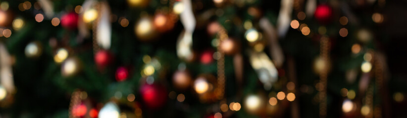 Christmas blurred background. Dressed up Christmas tree with ribbons and gold and red balls.