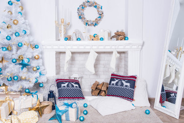 family holiday concept. Merry Christmas and Happy Holidays. Studio with Christmas decor. Winter home decor. Christmas tree, fireplace with firewood Boxes with gifts and golden and blue bows. Xmas