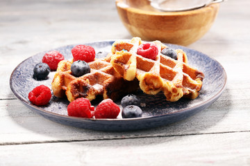 waffles with fresh blueberries, sugar and raspberries.