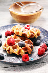 waffles with fresh blueberries, sugar and raspberries.