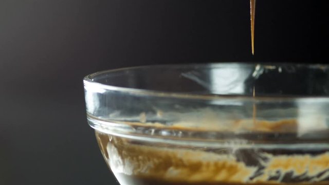 Liquid chocolate in a glass container. The corolla rises above the glass container and the shekolad flows in a small stream. Confectionery. A confectioner prepares a dessert, sauce.