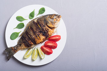 Fried fish dorado with lime , tomatoes and spinach