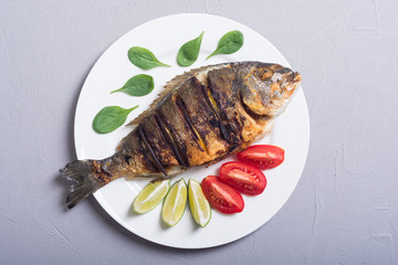 Fried fish dorado with lime , tomatoes and spinach