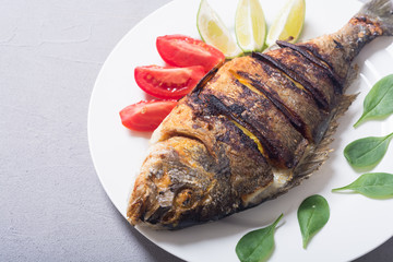 Fried fish dorado with lime , tomatoes and spinach