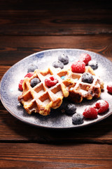 waffles with fresh blueberries, sugar and raspberries.
