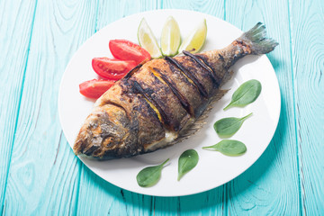 Fried fish dorado with lime , tomatoes and spinach