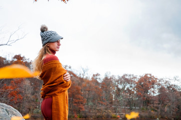 Fototapeta na wymiar Travel concept. Woman in warm hat and autumn clothes looking at lake and forest