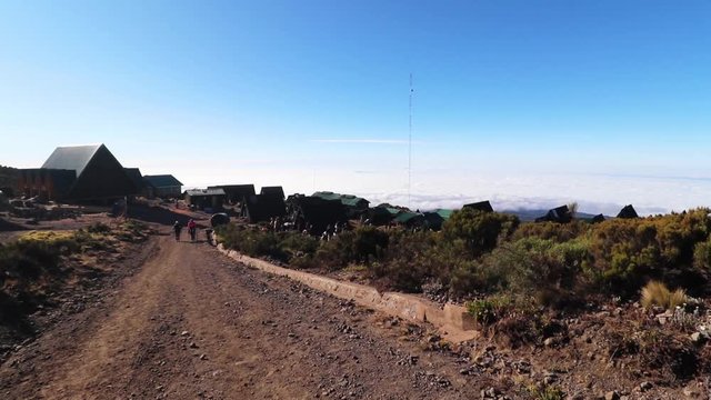 Static shot of a group of people hiking to a small town, on mount Kilimanjaro, on a sunny day, at Horombo hut, in Tanzania, Africa