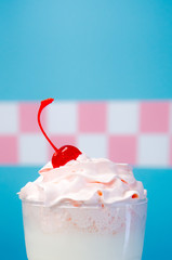 Glass of milkshake with whipped cream and cherry