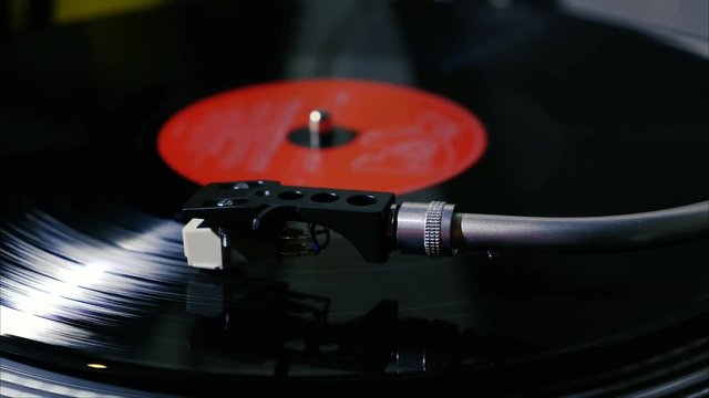 A black vintage vinyl record spins on a turntable with needle