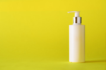 White bottle of moisturizing lotion on yellow background with copy space. Minimalism style. Skin care, body treatment, beauty concept