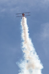 Biplane at the aerobatic show with big white smoke trail