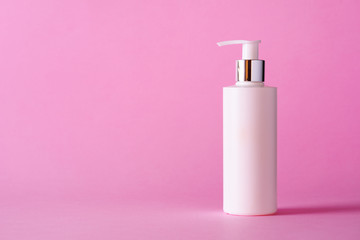 White bottle of moisturizing lotion on pink background with copy space. Minimalism style. Skin...