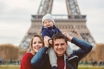 Young family, mother, father and baby boy in Paris with Eiffel tower on background. Travel theme...