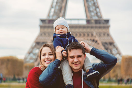 Young family, mother, father and baby boy in Paris with Eiffel tower on background. Travel theme image