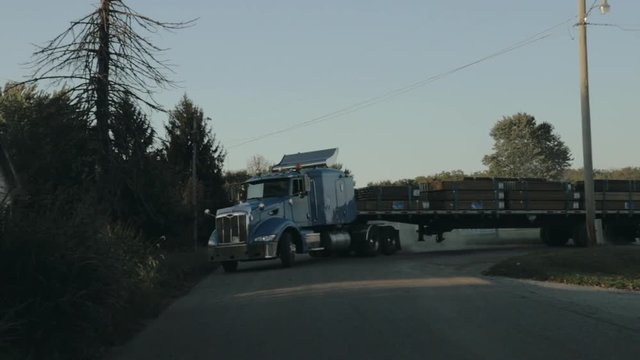 Peterbilt semi truck pulling out of yard and driving down the street front view in slow motion