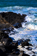 Pacific Ocean waves crashing into a rock formation at Mugu Rock in Malibu, California