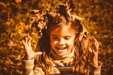 Happy little girl in the fairy autumn forest ,collecting the gold plates Portrait of attractive young girl outdoors