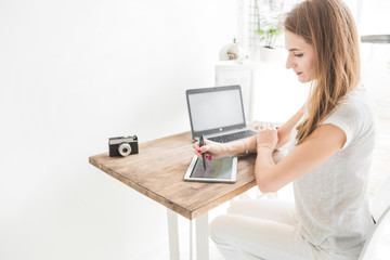 Fototapeta premium Young business woman working at home and draws on the tablet. Creative Scandinavian style workspace