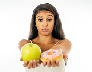 Attractive young woman on a diet deciding between an apple and a doughnut