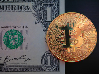 one gold bitcoin lay on one dollar bill