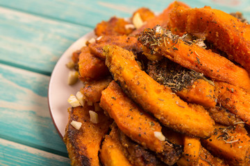 Chopped baked pumpkin with spices at blue background