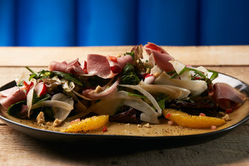 Smoked duck breast with fresh vegetable salad on wooden table ba