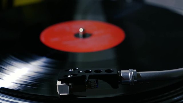 A black vintage vinyl record spins on a turntable with needle