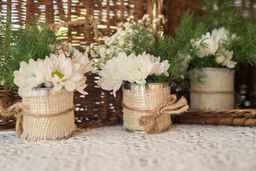 White flower inside a glass jar with woody background