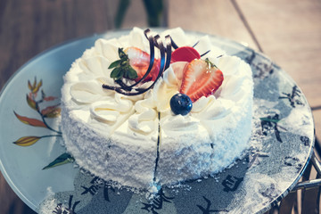 Blured for background.Homemade vanilla birthday cake decorated with strawberries, blueberries.