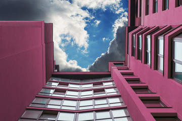 Multi-storey building of purple in the background of the sky with clouds.