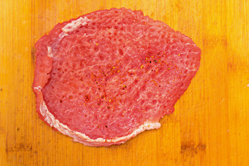 Slices of fresh pork sirloin meat with a metallic hammer for beating meat on wooden cutting board