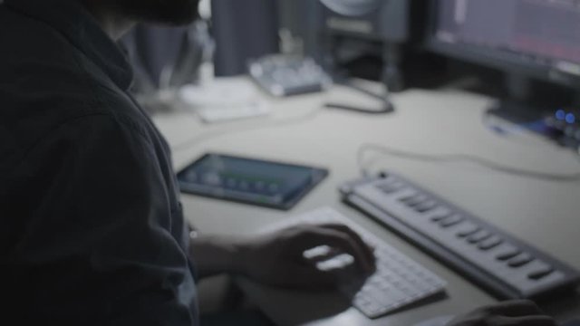 Producer, musician creating a beat on a drum pad in a recording studio