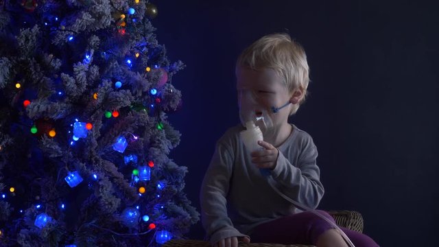 Caucasian blond child is crying from spasm of bronchitis and inhales vapors containing medications from inhaler to stop choking. Medical procedures. Respiratory medicine. Bronchitis, asthmatic problem