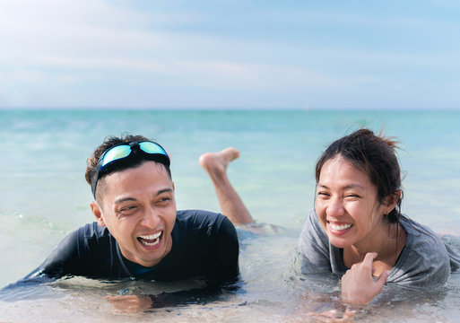 Happy Young Asian Couple  Lying On Tropical Beach In Southeast Asian,people Having Fun.