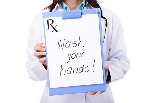 Healthcare professional holding a clipboard to show a message that reads "Wash your hands!"