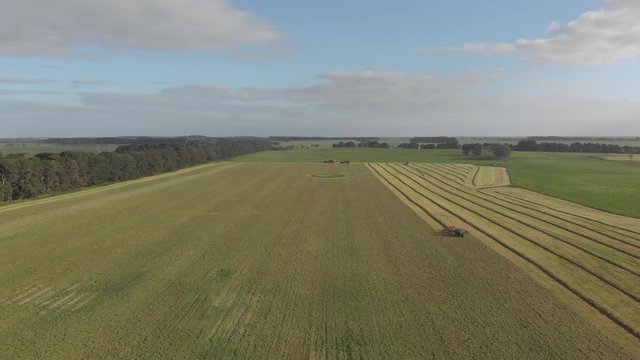 Distant straight aerial shot above rake tractor working on huge paddock.