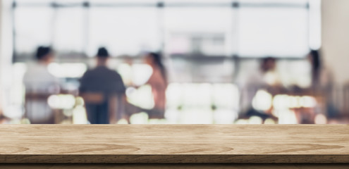 Empty wood table with blur people in coffee shop background bokeh light and leaf foreground,Mock up for display or montage of product,Banner for advertise on online media,business presentation.