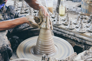 close up professional potter's hand making Thai style pot lid on a potter's wheel in pottery villages at Ko Kret, Nonthaburi province, Thailand (selective focus)