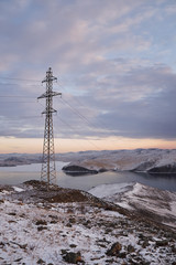 Power tower against clouds and blue sky on Baikal lake