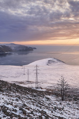 Power tower against clouds and blue sky on Baikal lake