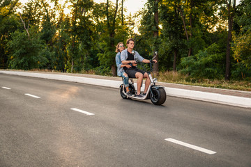 Lovely young couple dating with electric bike. Modern city life and transportation. She hugs him