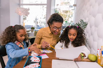 Student reading. Caring smart beautiful teacher wearing glasses teaching her beautiful student reading